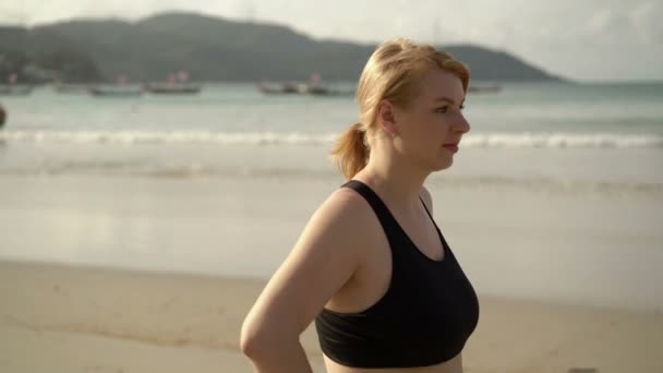 Mujer rubia joven haciendo ejercicios deportivos en una playa — Vídeo de stock