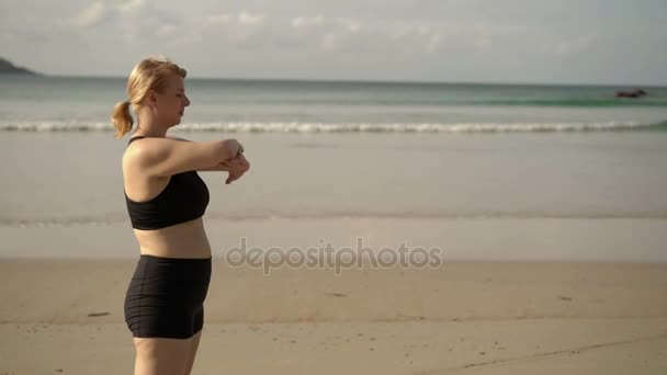 年轻的金发女子，使体育锻炼在海滩上 — 图库视频影像