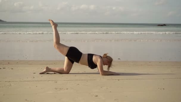 Genç sarışın kadın spor egzersizleri bir plajda yapma — Stok video