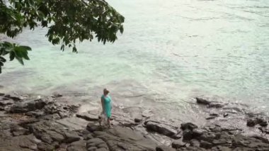 Kayalık sahilde yürüyen genç kadın