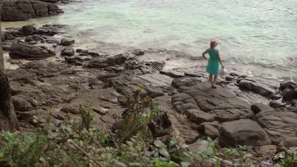 Tânără femeie care stă pe plaja stâncoasă — Videoclip de stoc