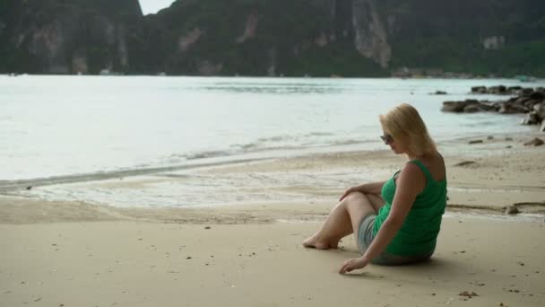 Mujer sentada sola en la playa salvaje — Vídeos de Stock