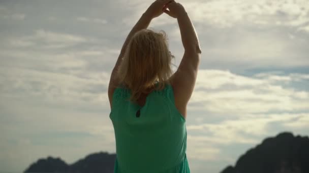Женщина ходит одна по дикому пляжу и поднимает руки вверх — стоковое видео