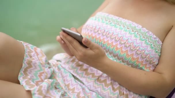 Jonge vrouw op een strandstoel met mobile — Stockvideo