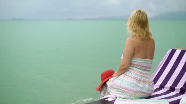 Jeune femme sur une chaise longue de plage — Video