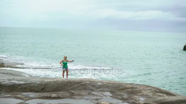 Młoda kobieta biorąc zdjęcie z selfie stick w pobliżu morza — Wideo stockowe