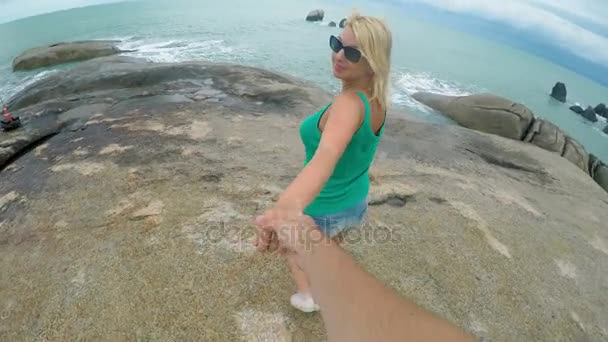 Junge Frau läuft am felsigen Strand und hält Mann an der Hand — Stockvideo