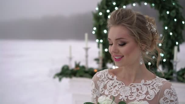Jonge vrouw in witte jurk in de buurt van open haard decoratie op bevroren meer — Stockvideo