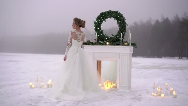 Young woman in white dress near fireplace decoration on frozen lake — Stock Video
