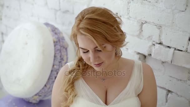 Jeune femme blonde mignonne en robe de mariée avec bouquet de fleurs posant en studio — Video