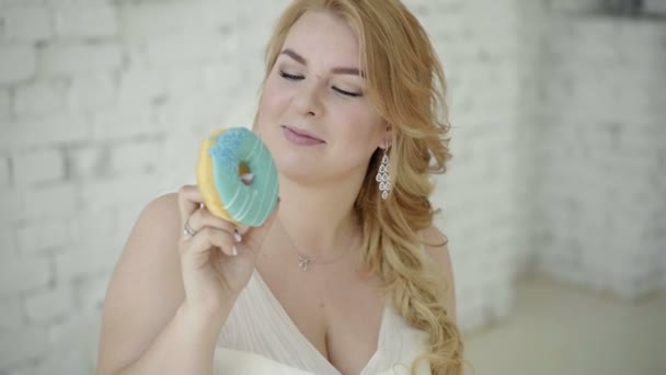 Bonito jovem loira em vestido de noiva posando em estúdio com donut — Vídeo de Stock