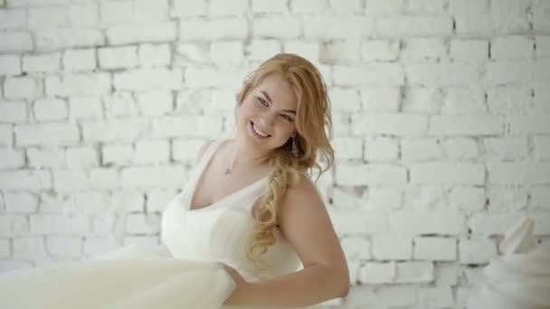 Cute young blonde woman in wedding dress posing and dancing in studio on background huge ice cream and macaroni — Stock Video