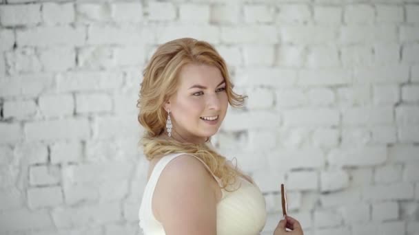 Cute young blonde woman in wedding dress posing in studio with candy — Stock Video