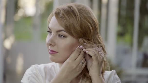 Niedliche junge blonde Frau in Dessous trägt Ohrringe — Stockvideo