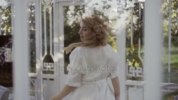 Симпатична молода блондинка з великими грудьми в нижній білизні біля панорамного вікна кружляє — стокове відео