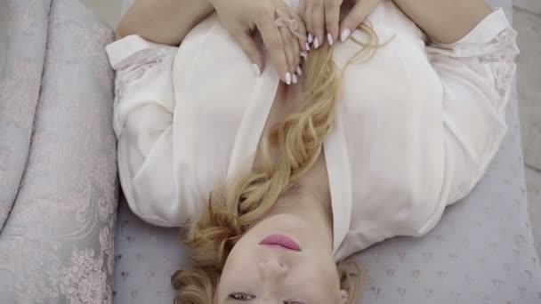 Roztomilá mladá blondýnka s velkými prsy na prádlo leží na pohovce a dotýká její tělo — Stock video