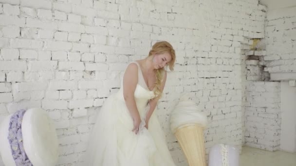 Cute young blonde woman in wedding dress posing for photographer in studio steadicam — Stock Video