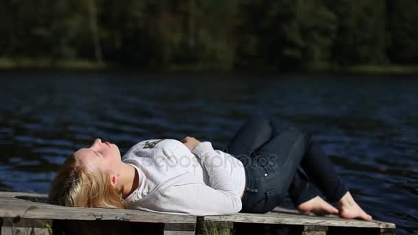 湖の近くに座っていた若い女性 — ストック動画