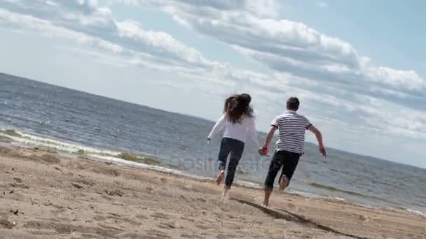 Junges reizendes Paar läuft an einem Strand — Stockvideo