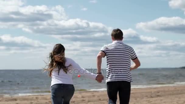 Junges reizendes Paar läuft an einem Strand — Stockvideo