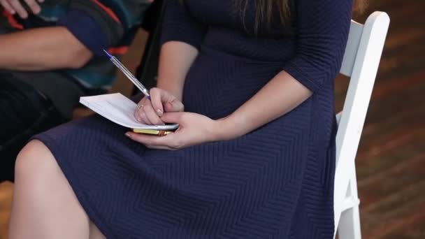 Mulher escrevendo em caderno sobre palestra — Vídeo de Stock