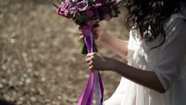 Mladá žena v bílém prádle s kyticí venku — Stock video