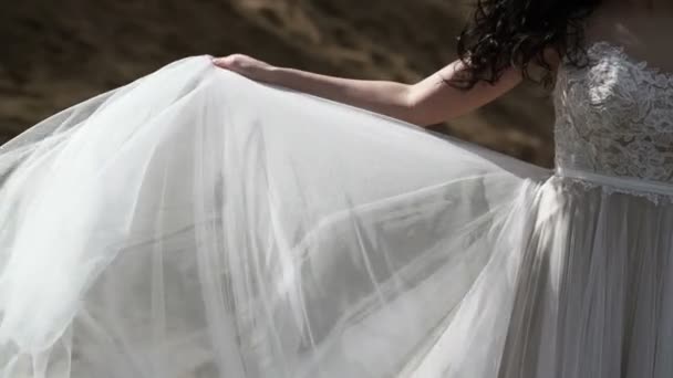 Невеста в свадебном платье размахивает тряпкой на ветру — стоковое видео