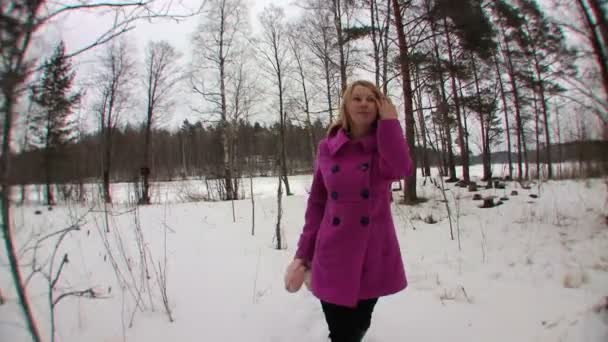 Mujer rubia joven en abrigo rosa caminando en el bosque de invierno — Vídeo de stock