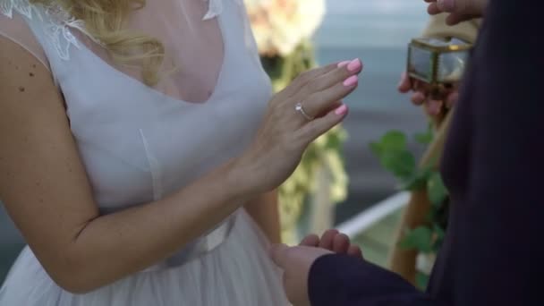 Жених надевает обручальное кольцо на руку невесты — стоковое видео