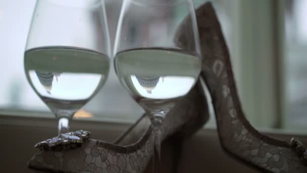 Zenske bílé boty a dvě sklenice šampaňského — Stock video