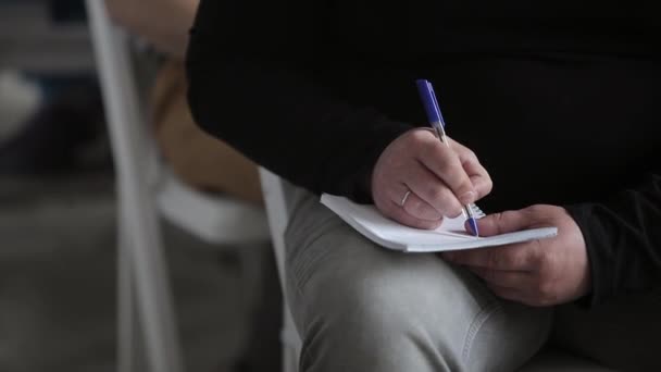 Человек, пишущий в блокноте по лекции — стоковое видео