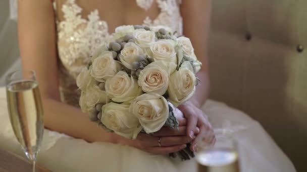 Kavkazská mladá nevěsta ve svatebních šatech sedí na pohovce s kyticí — Stock video