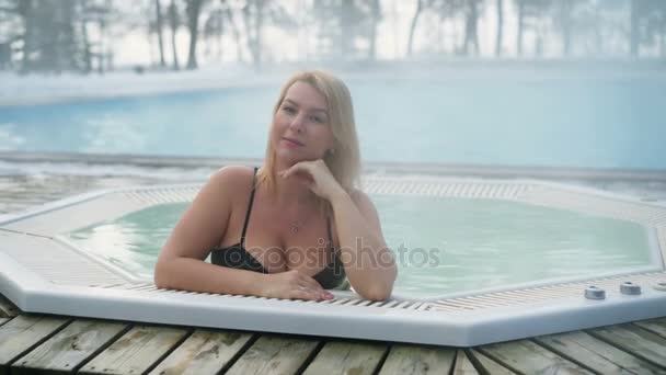 Jeune femme blonde dans la baignoire jacuzzi en plein air en hiver — Video