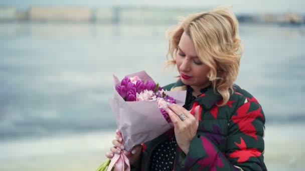 Jeune femme blonde avec bouquet de fleurs sur une rue de la ville — Video