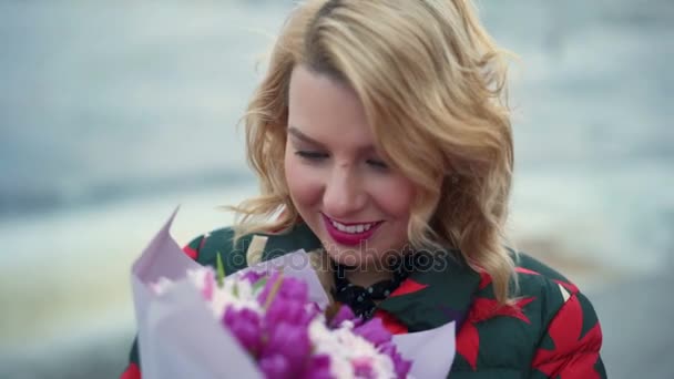 街で花の花束と若いブロンドの女性 — ストック動画