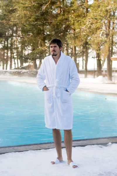 Bornoz kış açık yüzme havuzunun yanında genç adam