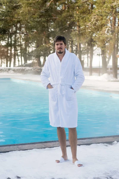 Bornoz kış açık yüzme havuzunun yanında genç adam