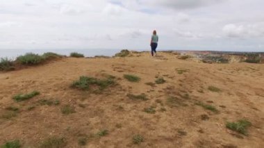 Deniz kenarında bir kayaya genç kadın yürüyor