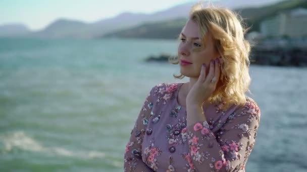 Молода блондинка в сукні біля моря — стокове відео