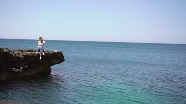 年轻的金发女子，在海边的岩石上 — 图库视频影像