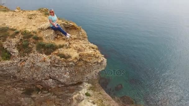 Mladá žena sedící na skále u moře — Stock video