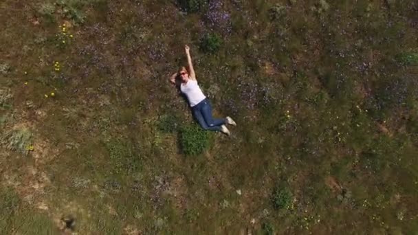 Young blonde woman lies in a field — Stock Video