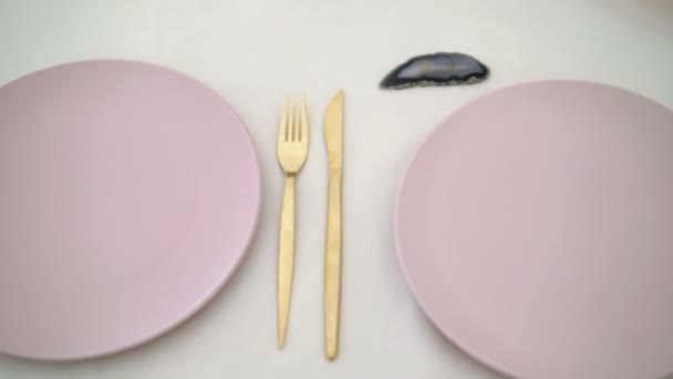Розовые тарелки и золотой нож и вилка — стоковое видео