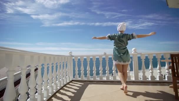 Jonge vrouw in badjas komt naar balkon — Stockvideo