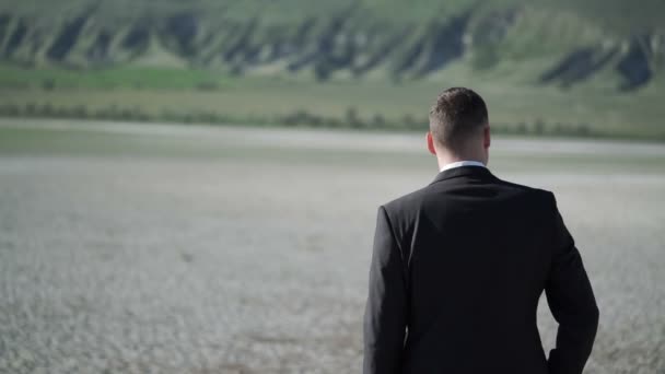 Jonge man in pak verblijft in een veld — Stockvideo