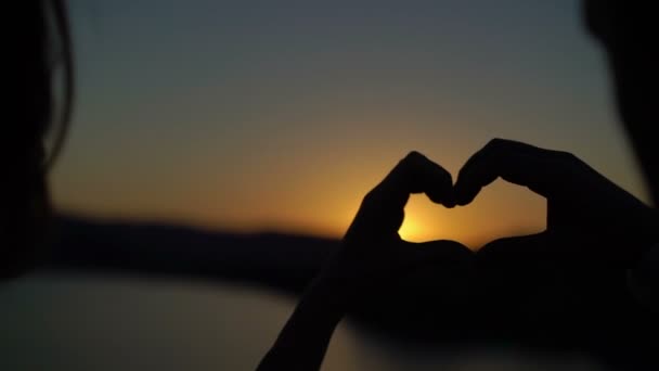 Pasangan muda membuat hati dari tangan saat matahari terbenam — Stok Video