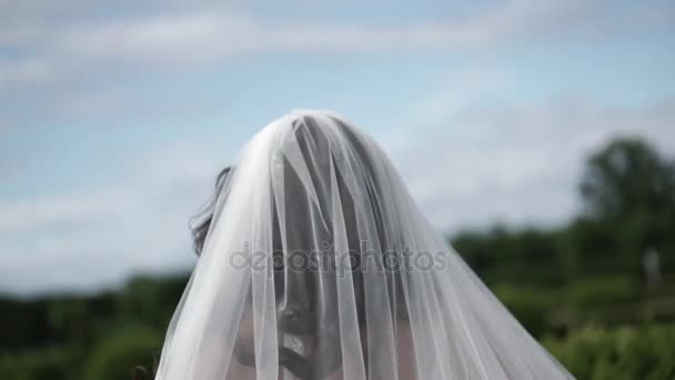 Novia caminando en un parque y agitando velo — Vídeos de Stock