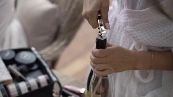 Jeune femme en peignoir ouverture bouteille de champagne — Video