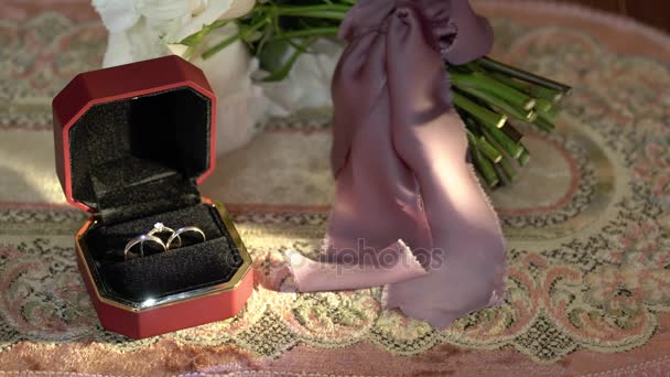 在一个红色的盒子和新娘捧花的三个结婚戒指。 — 图库视频影像