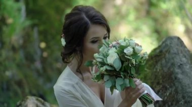 Şelale yakınındaki bir kayaya oturan genç kadın